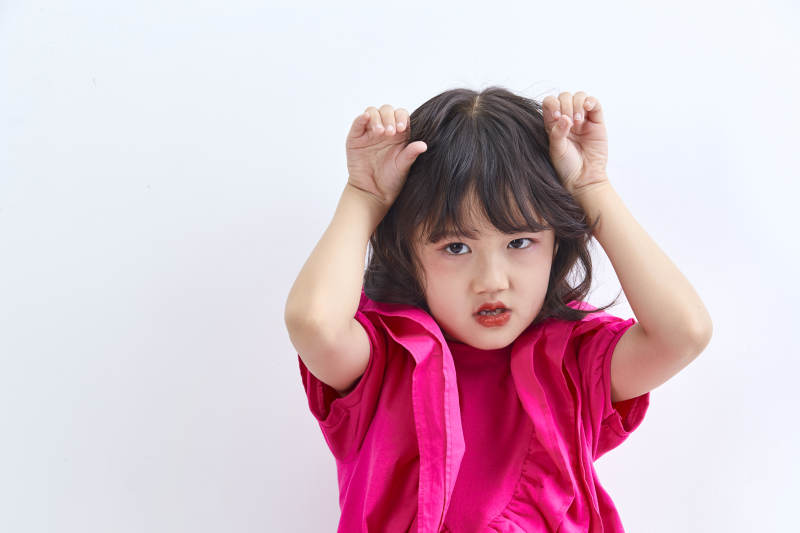 白色背景里坐在凳子上的可爱的亚洲小女孩儿童图片