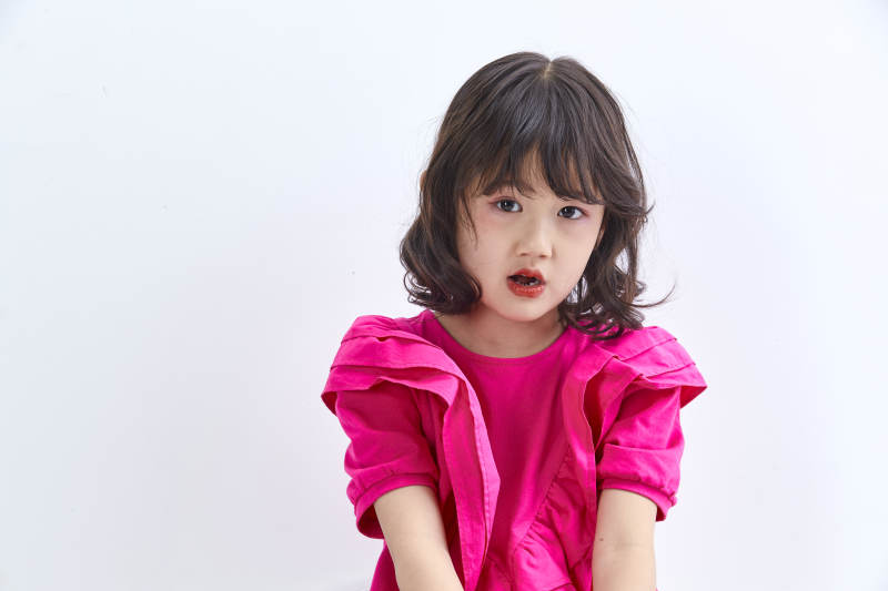 白色背景里坐在凳子上的可爱的亚洲小女孩儿童图片