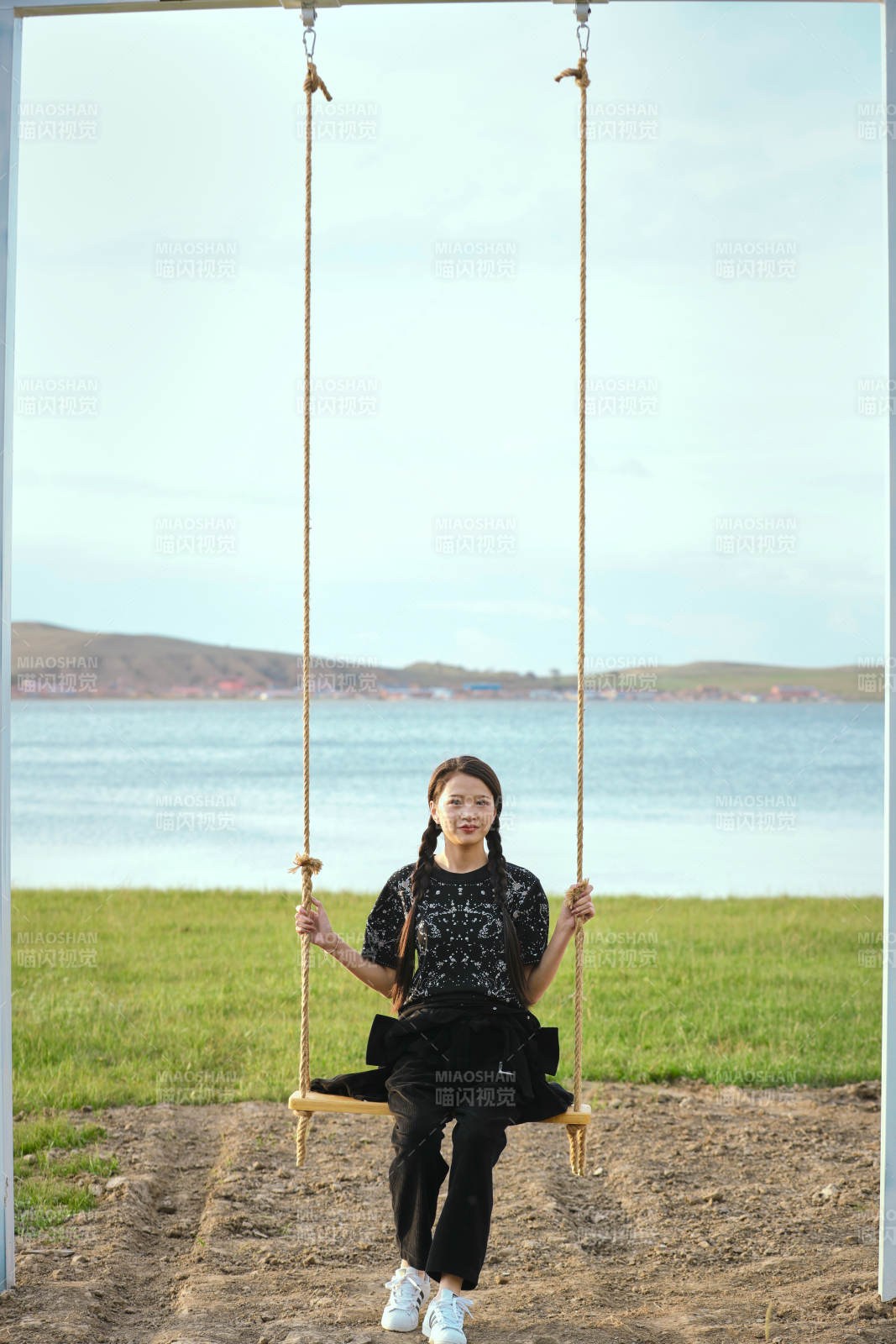 草原湖畔夕阳下荡秋千的亚洲少女图片