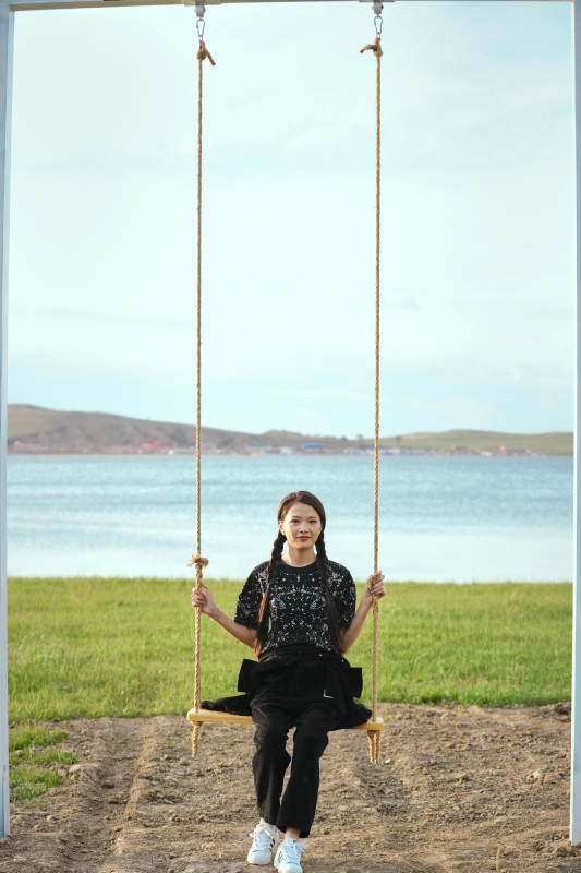 草原湖畔夕阳下荡秋千的亚洲少女图片