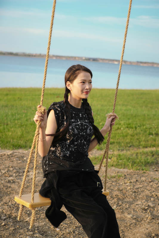 草原湖畔夕阳下荡秋千的亚洲少女图片