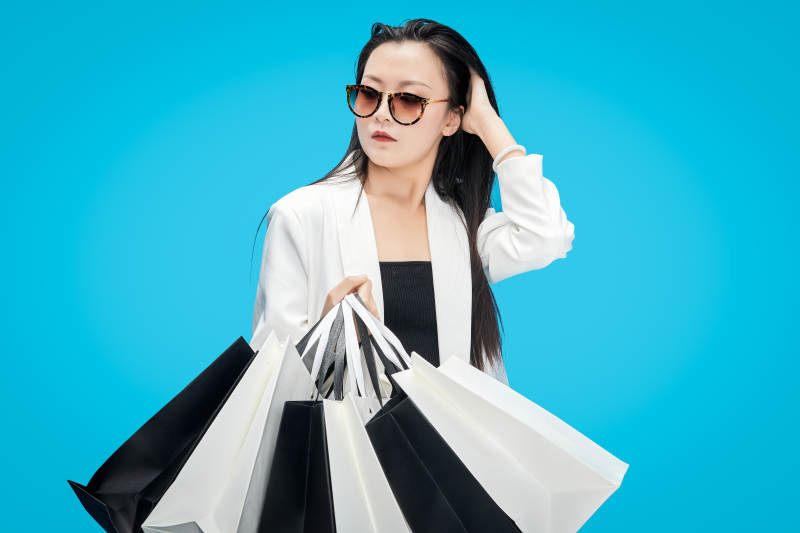 青蓝色背景下手提购物袋的亚洲时尚少女图片