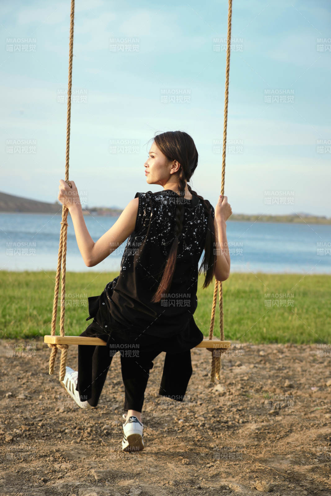 草原湖畔夕阳下荡秋千的亚洲少女图片