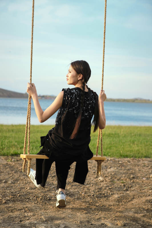 草原湖畔夕阳下荡秋千的亚洲少女图片