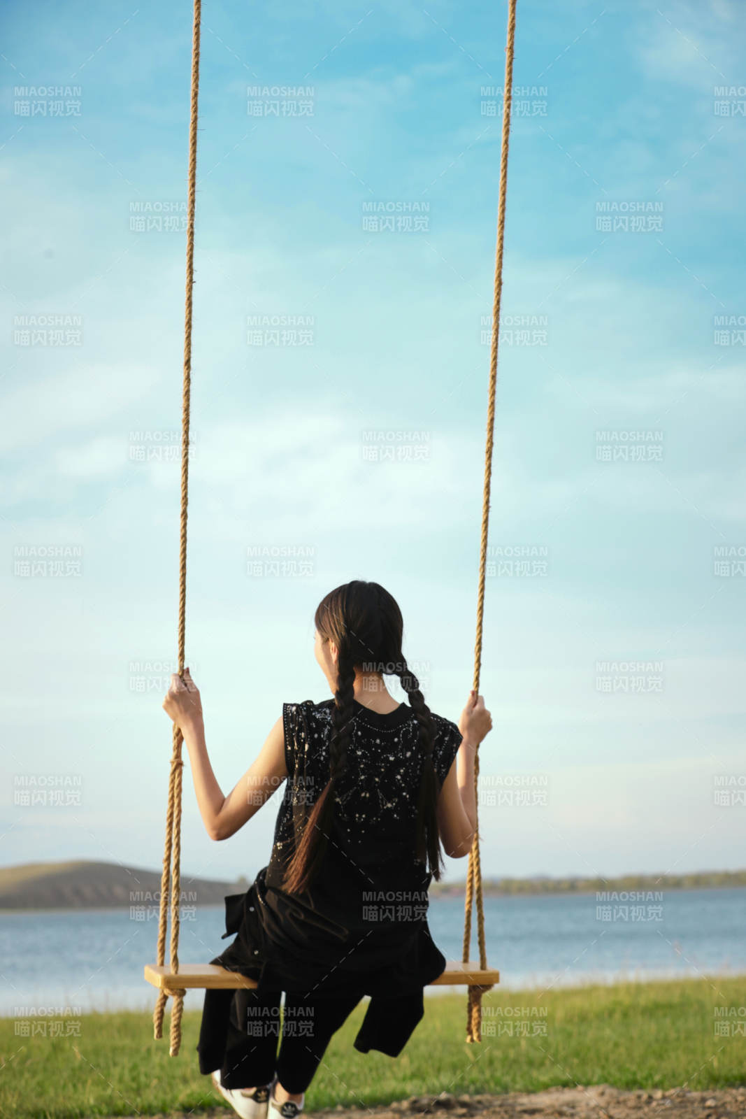 草原湖畔夕阳下荡秋千的亚洲少女图片