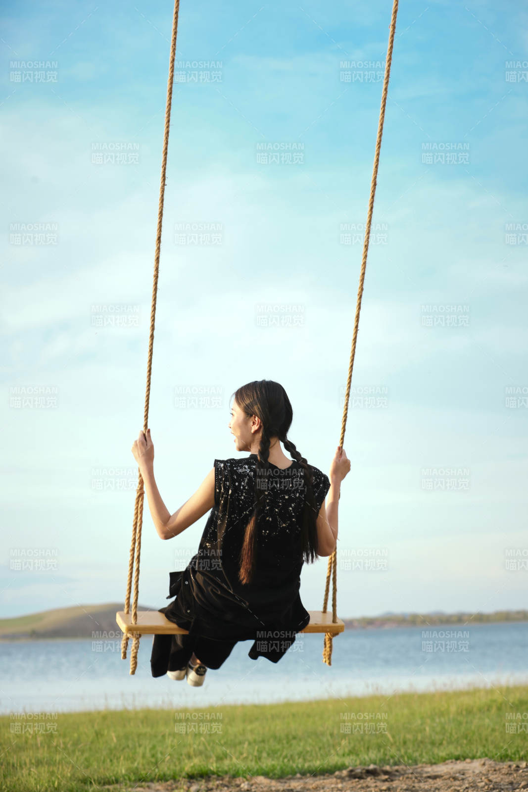 草原湖畔夕阳下荡秋千的亚洲少女图片