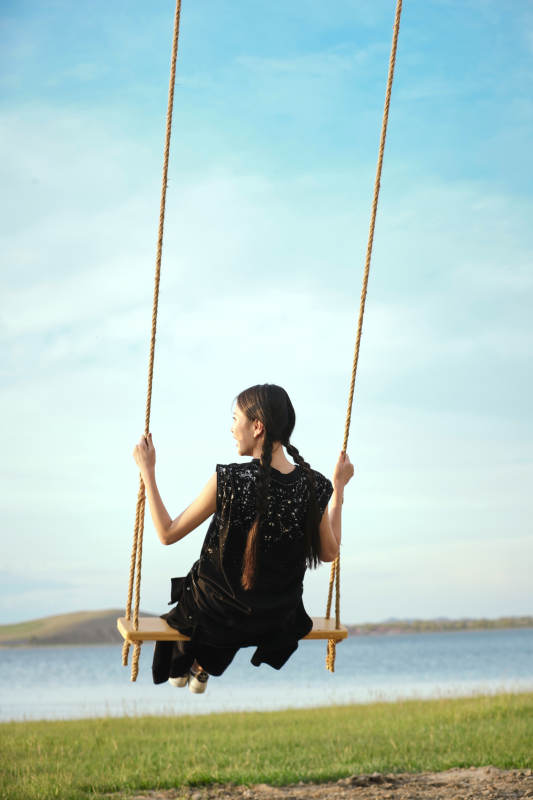 草原湖畔夕阳下荡秋千的亚洲少女图片