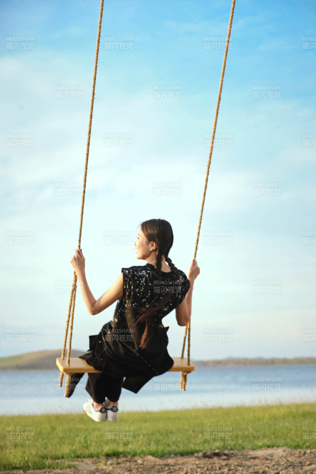 草原湖畔夕阳下荡秋千的亚洲少女图片