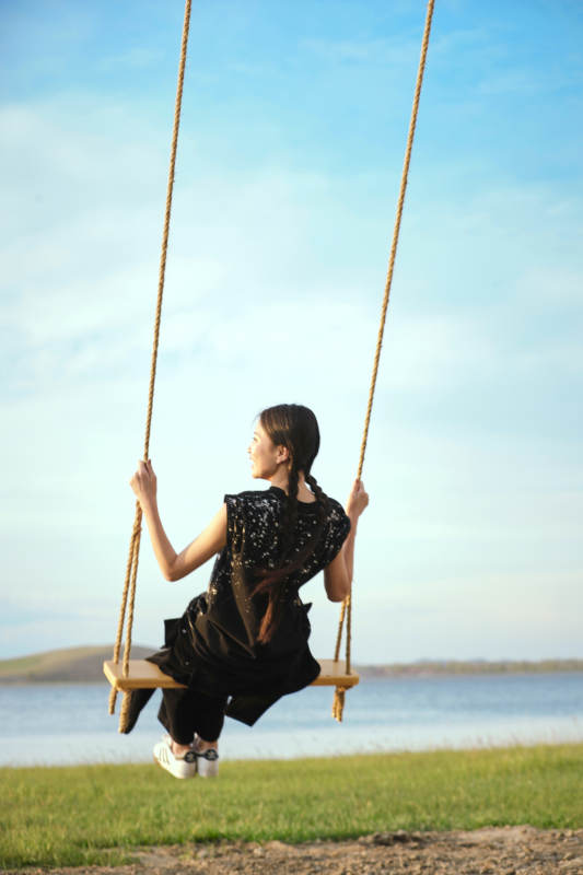 草原湖畔夕阳下荡秋千的亚洲少女图片