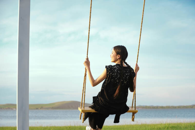 草原湖畔夕阳下荡秋千的亚洲少女图片