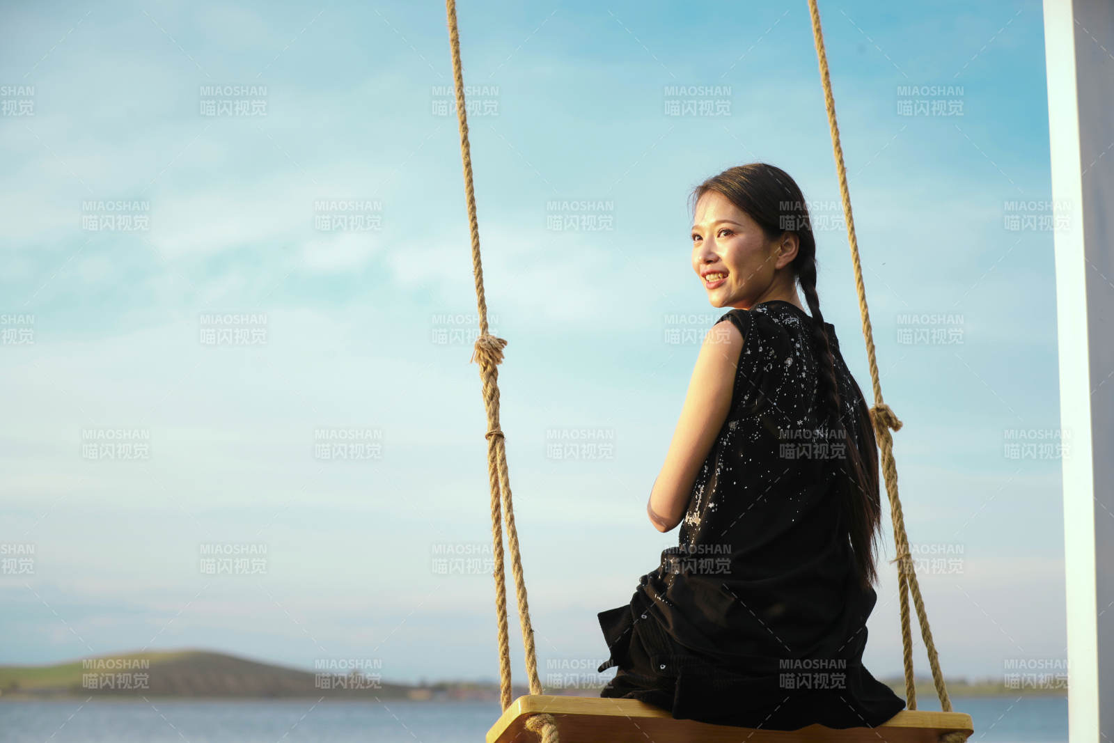 草原湖畔夕阳下荡秋千的亚洲少女图片
