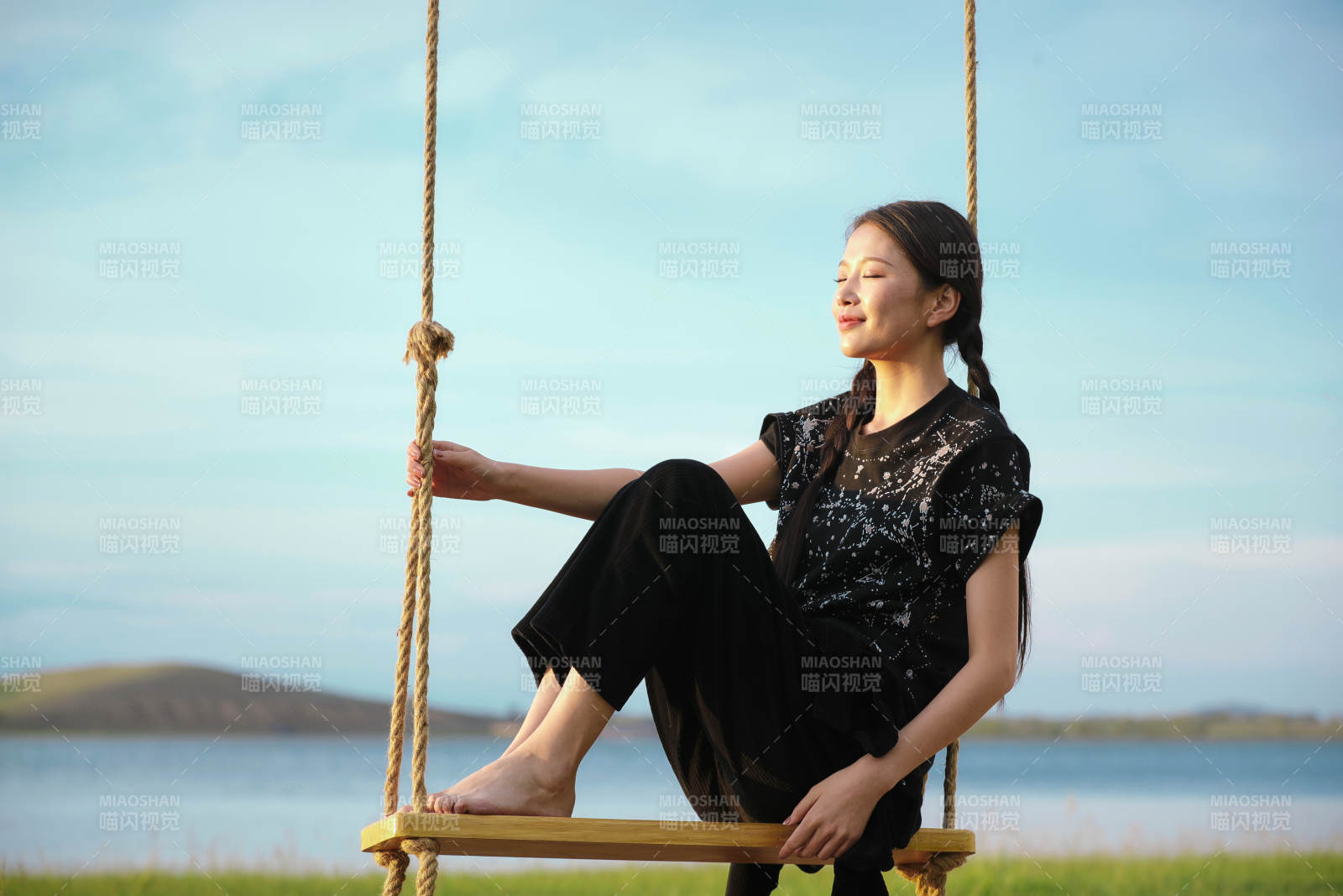 草原湖畔夕阳下荡秋千的亚洲少女图片