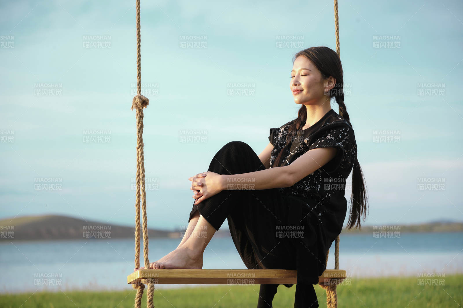 草原湖畔夕阳下荡秋千的亚洲少女图片