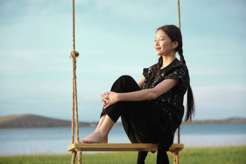 草原湖畔夕阳下荡秋千的亚洲少女图片