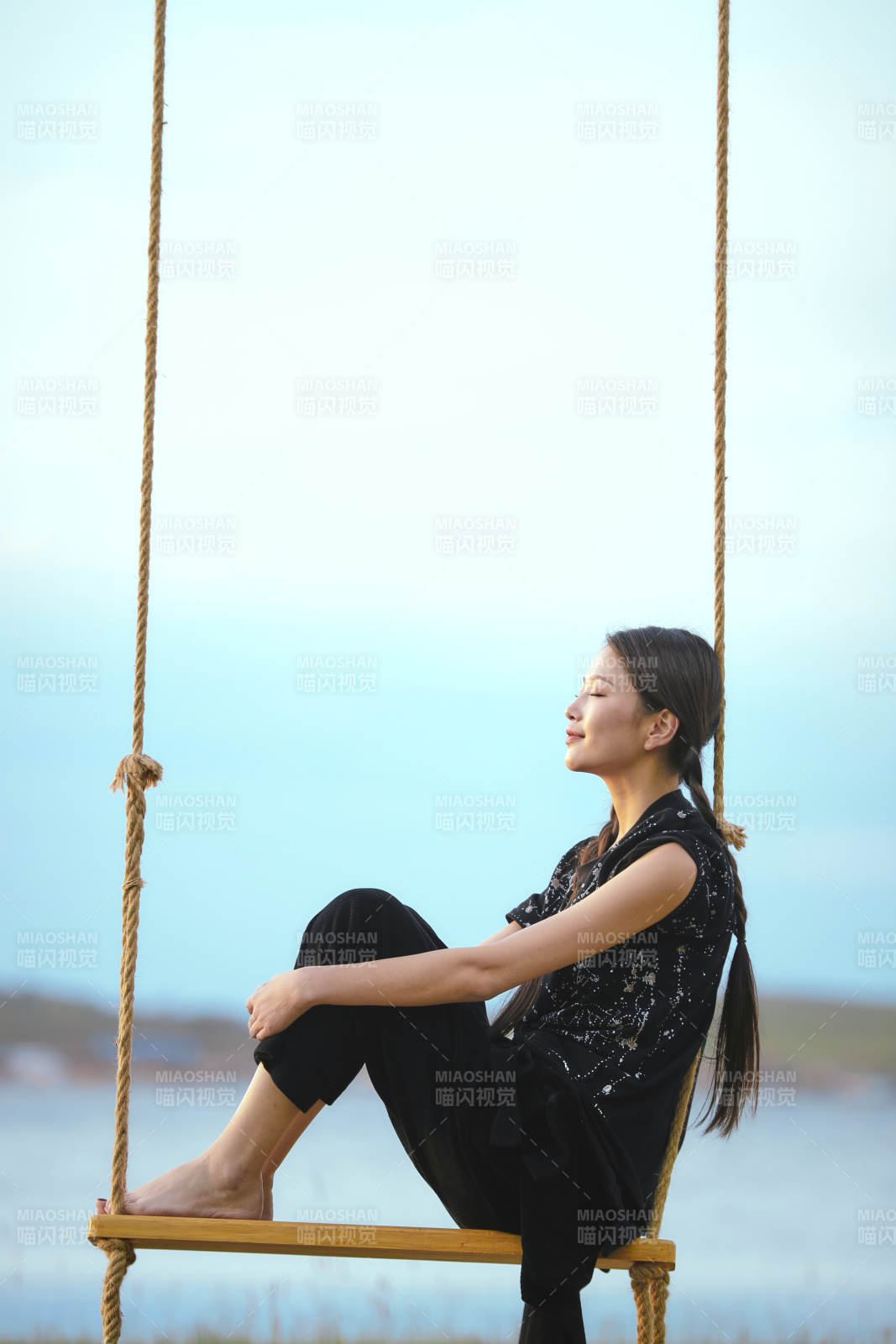 草原湖畔夕阳下荡秋千的亚洲少女图片