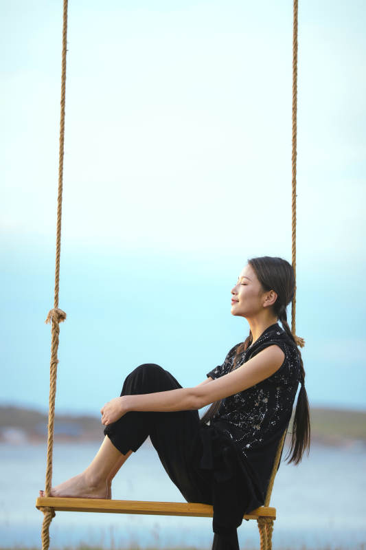 草原湖畔夕阳下荡秋千的亚洲少女图片