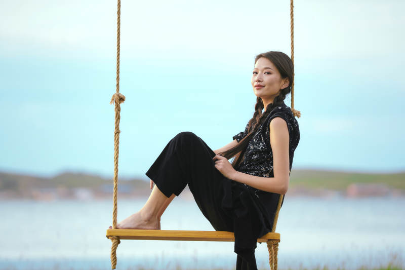 草原湖畔夕阳下荡秋千的亚洲少女图片