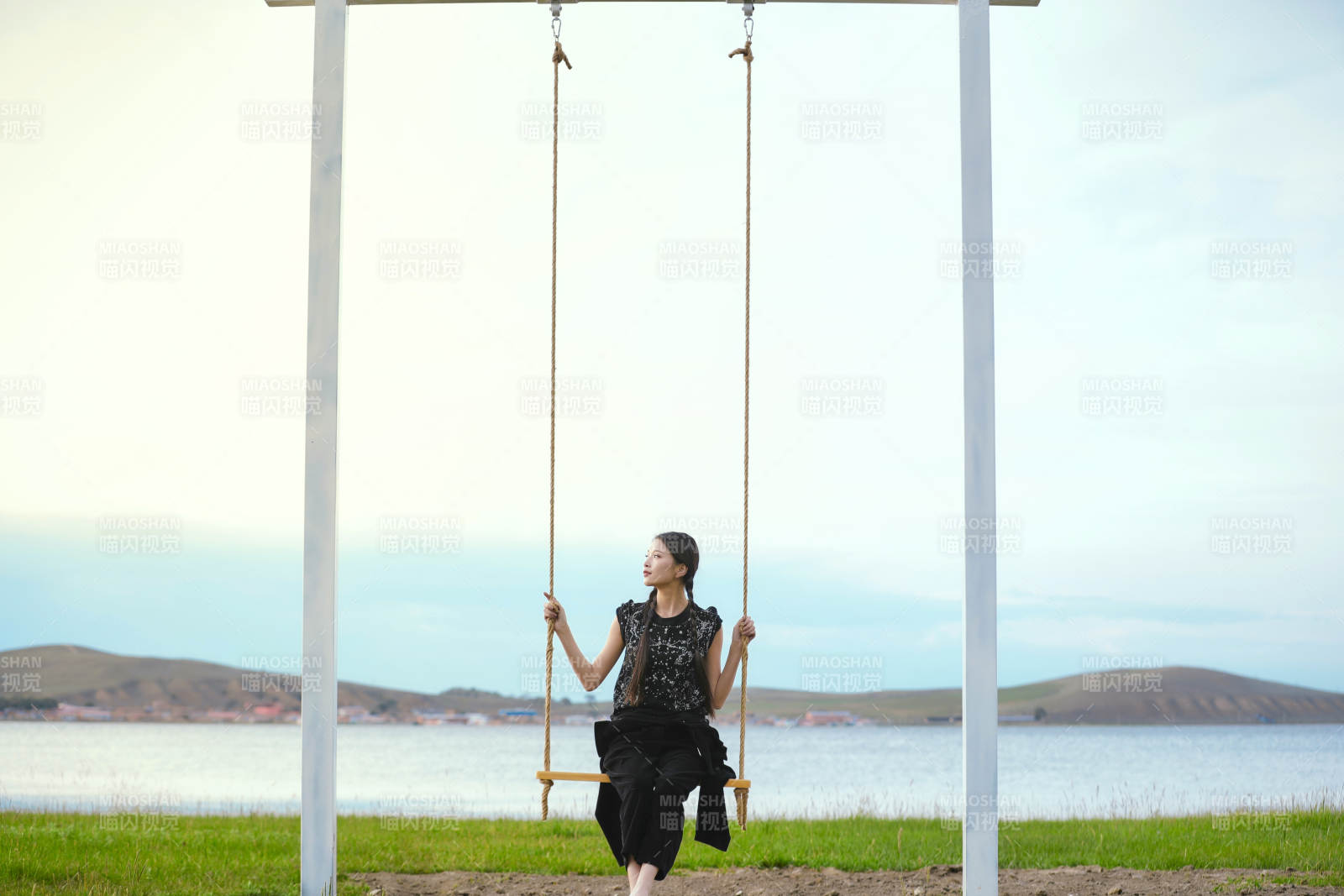 草原湖畔夕阳下荡秋千的亚洲少女图片