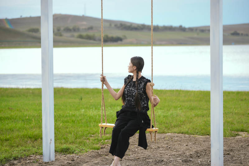 草原湖畔夕阳下荡秋千的亚洲少女图片