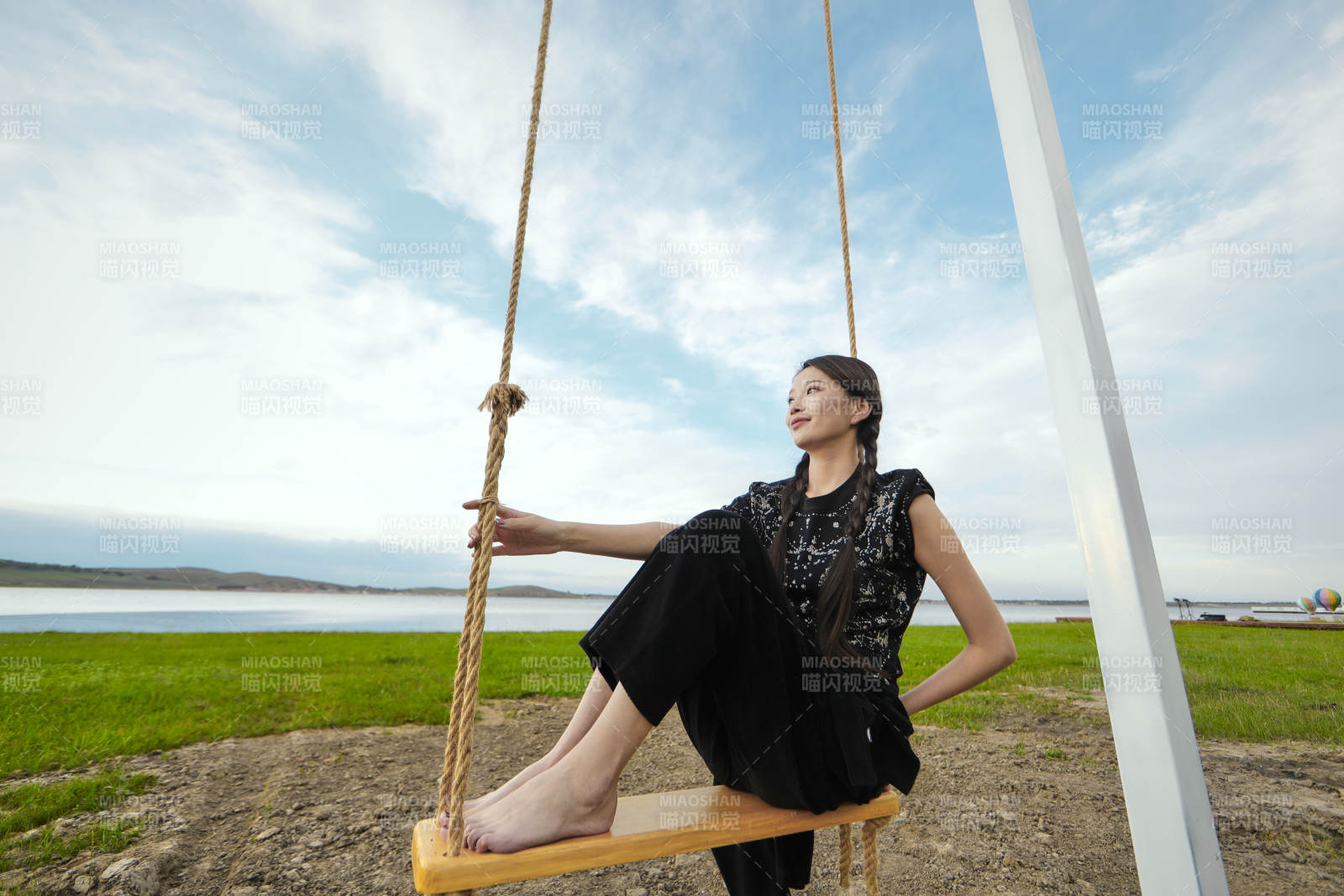 草原湖畔夕阳下荡秋千的亚洲少女图片
