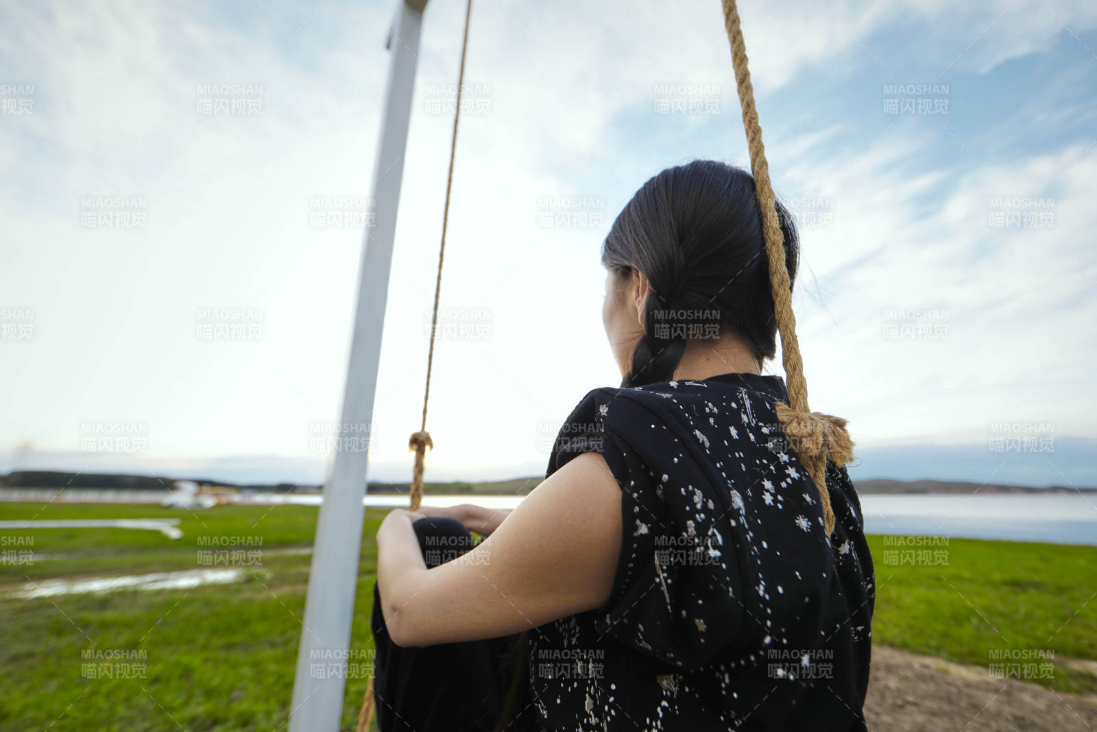 草原湖畔夕阳下荡秋千的亚洲少女图片