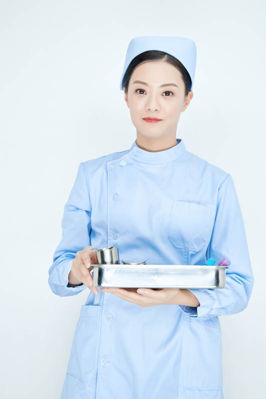 身穿护士服手抱化验托盘的年轻女护士图片