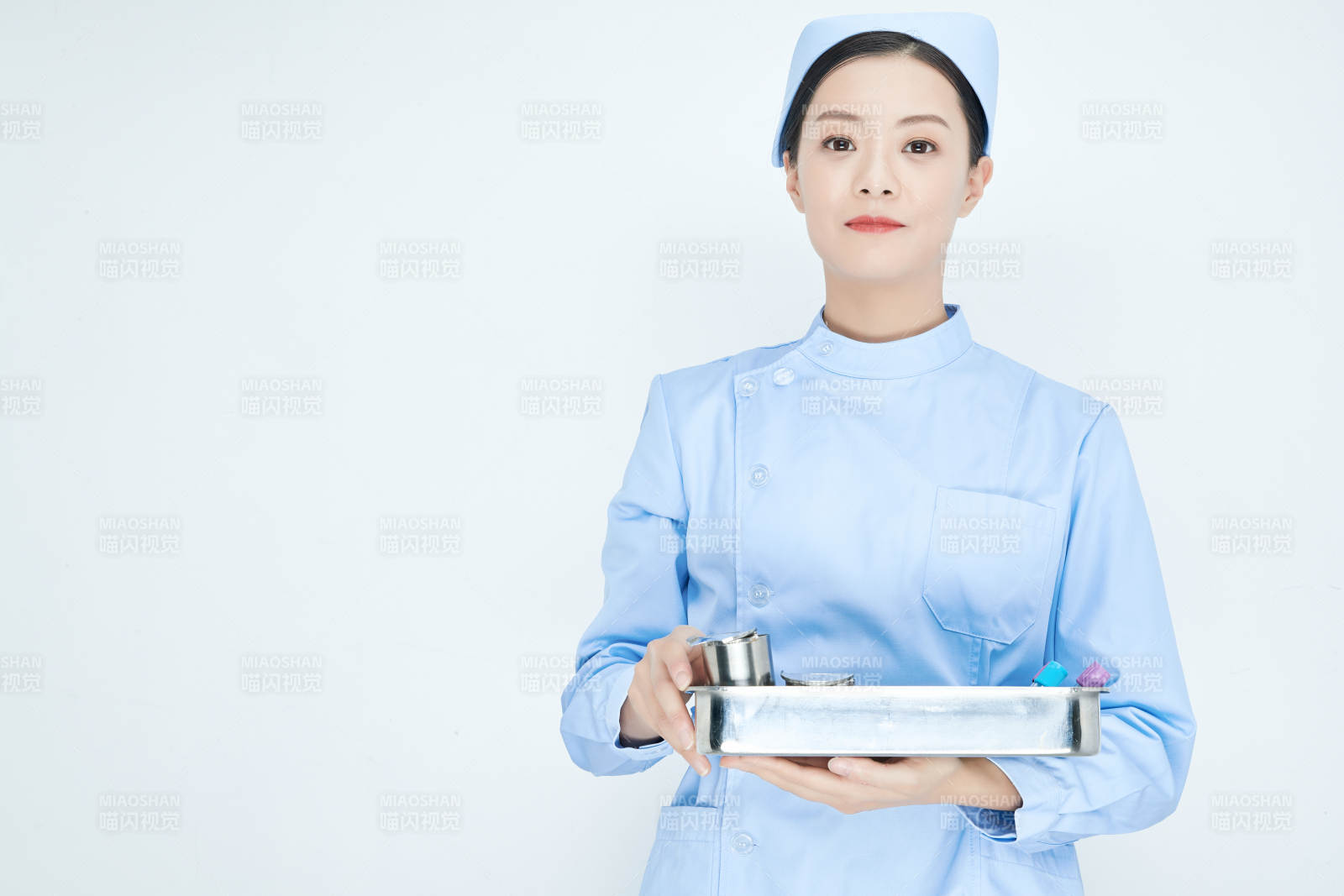 身穿护士服手抱化验托盘的年轻女护士图片