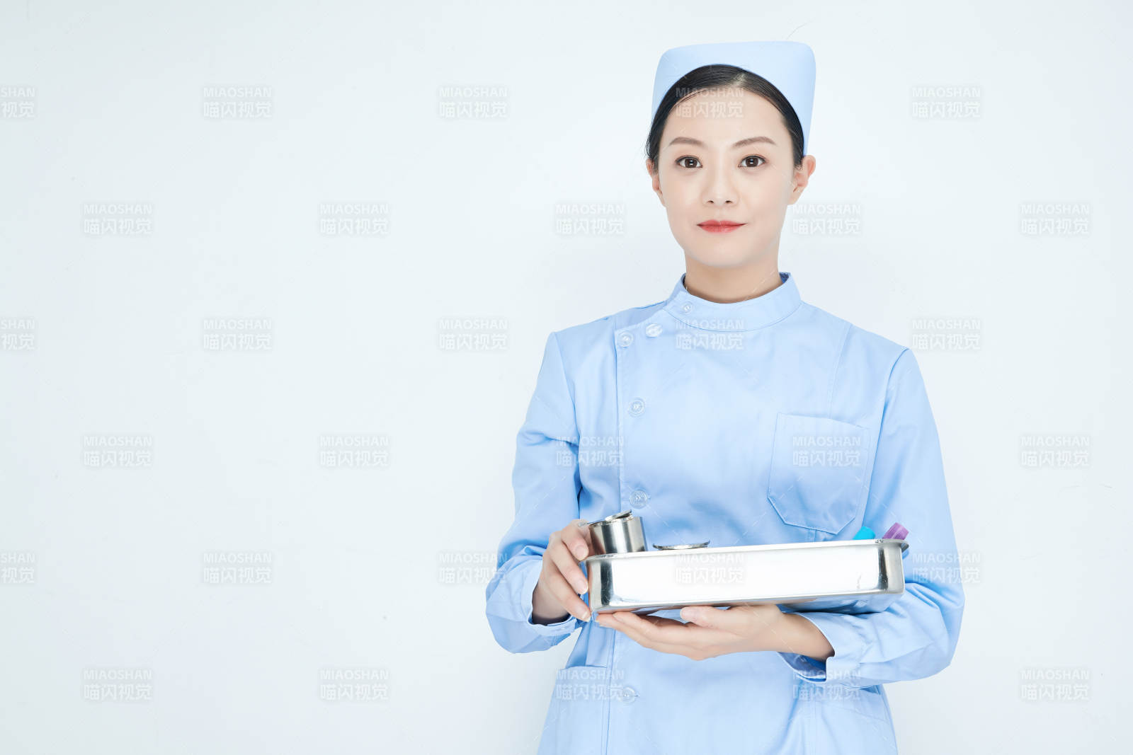 身穿护士服手抱化验托盘的年轻女护士图片