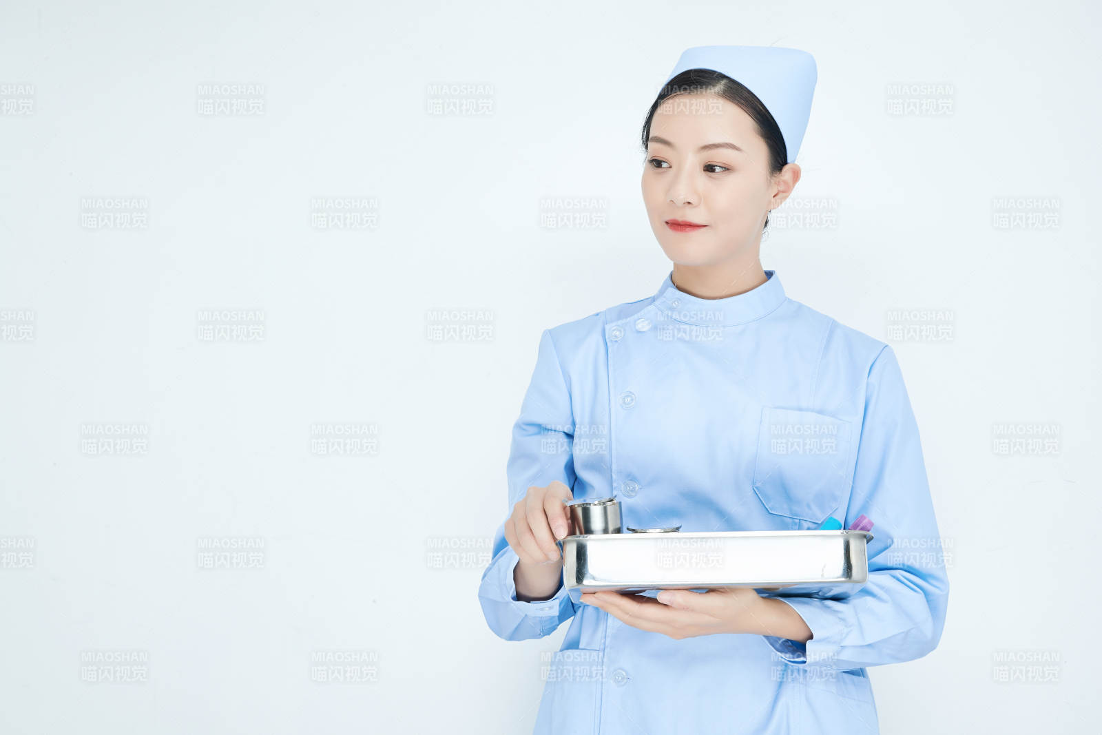 身穿护士服手抱化验托盘的年轻女护士图片