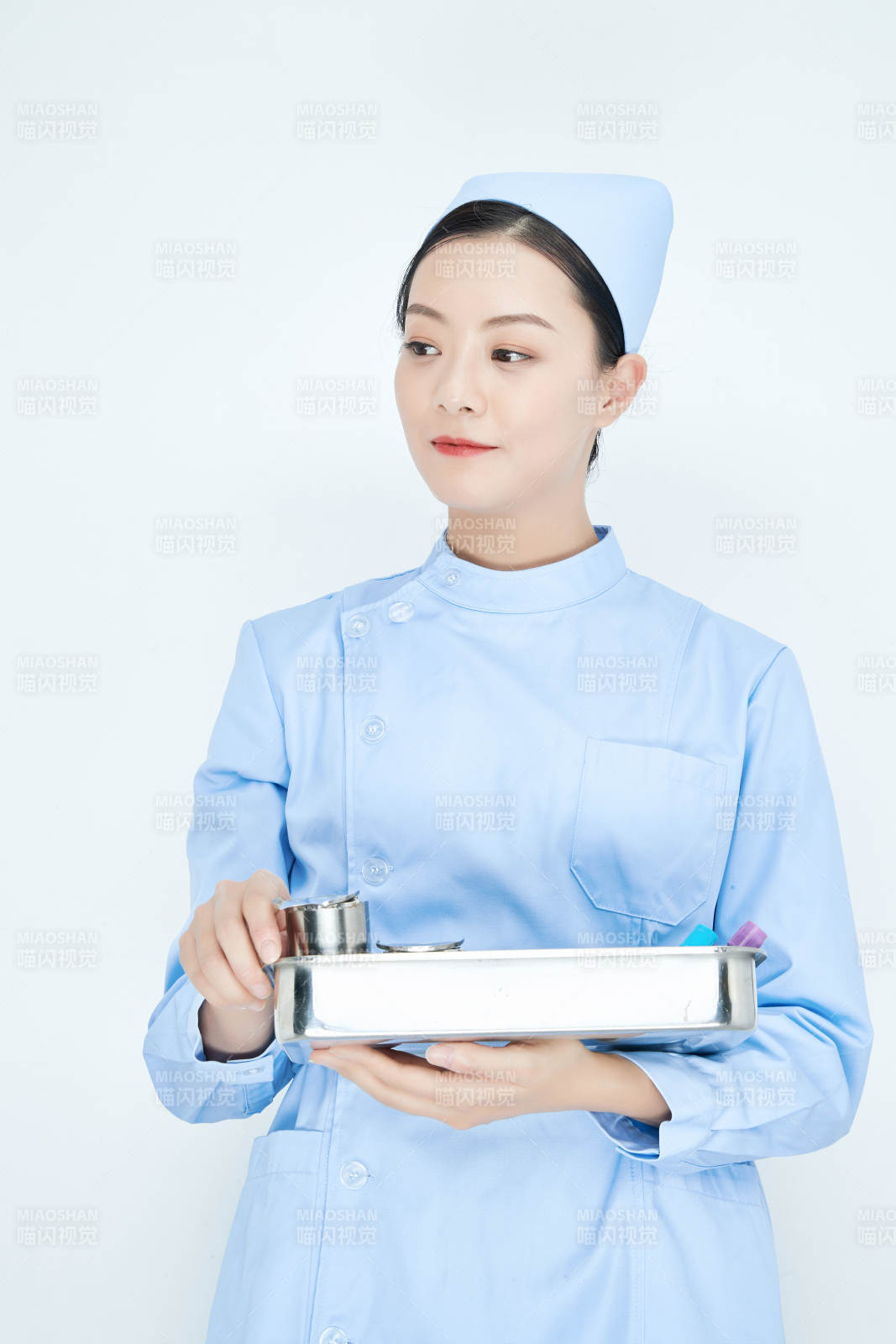 身穿护士服手抱化验托盘的年轻女护士图片