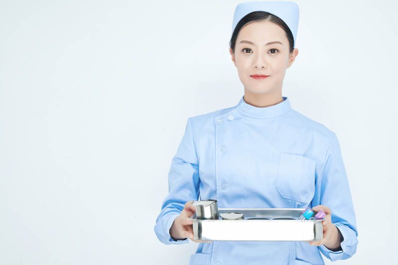 身穿护士服手抱化验托盘的年轻女护士图片
