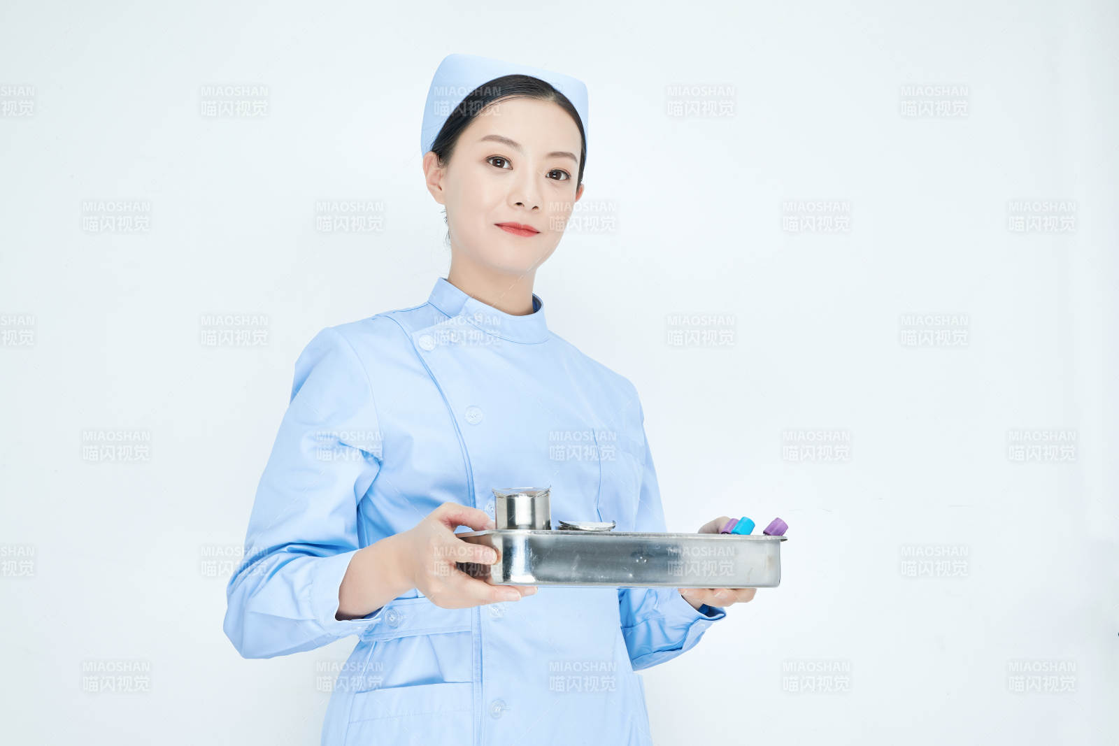 身穿护士服手抱化验托盘的年轻女护士图片