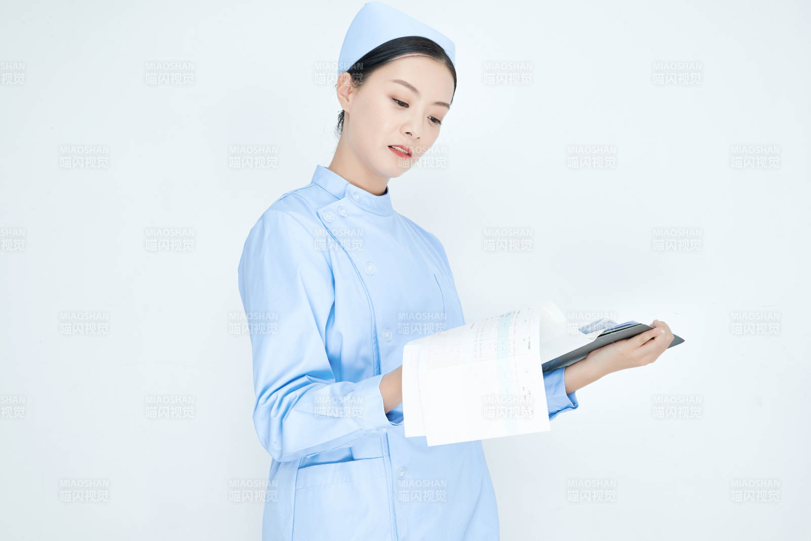 白背景里穿蓝色护士服手持病历夹的美女护士图片