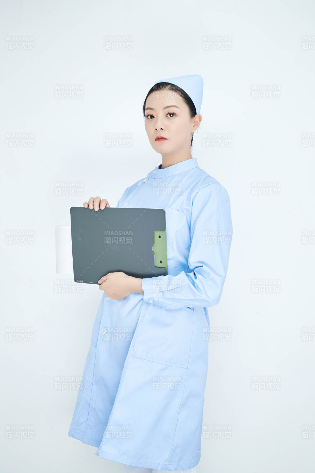 白背景里穿蓝色护士服手持病历夹的美女护士图片