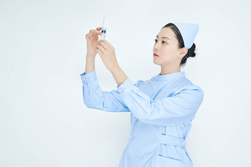 穿护士服戴口罩手执针筒的年轻女护士图片
