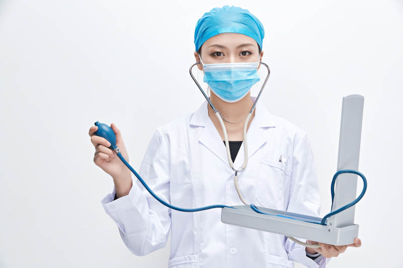 白色背景下手持血压计的门诊医生图片