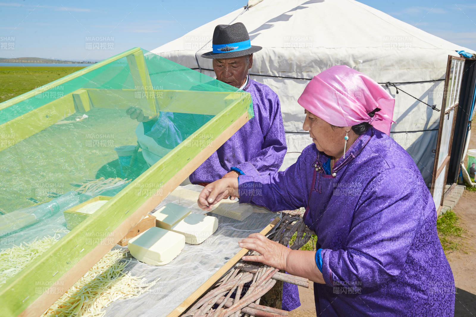 在蒙古包外晾晒奶制品的蒙古族中老年夫妻图片