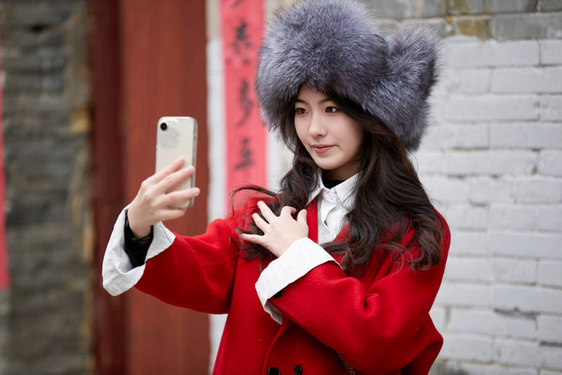 春节在老城古巷穿着喜庆服饰的美丽少女图片