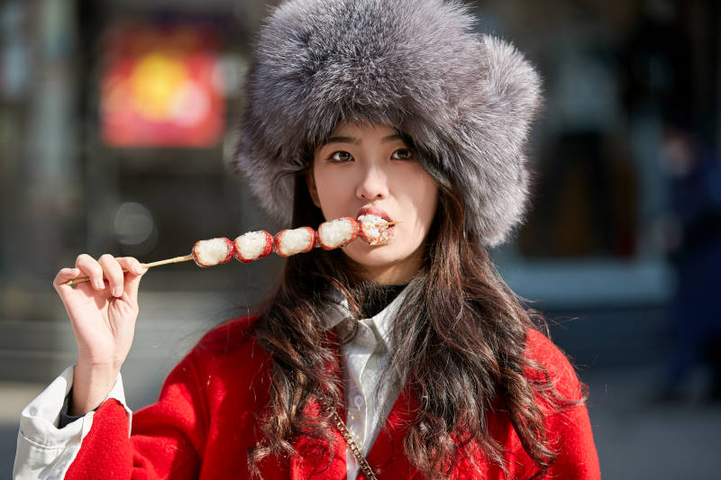穿着喜庆服饰吃糖葫芦的美丽少女图片