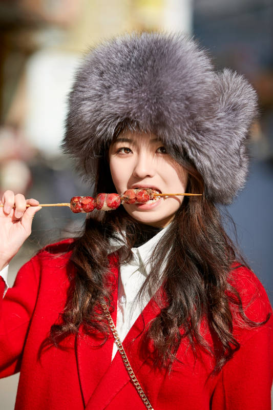 穿着喜庆服饰吃糖葫芦的美丽少女图片