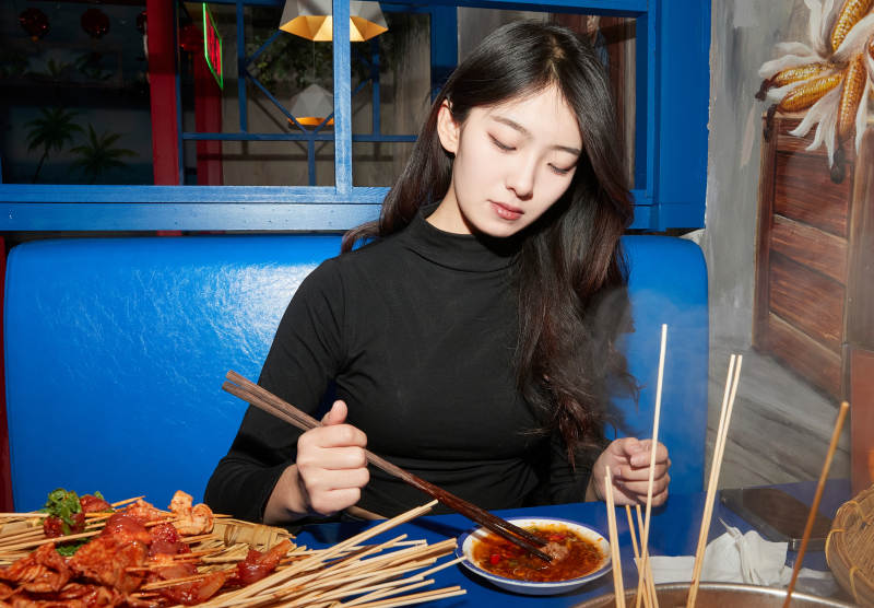 在饭馆吃成都串串的亚洲少女图片