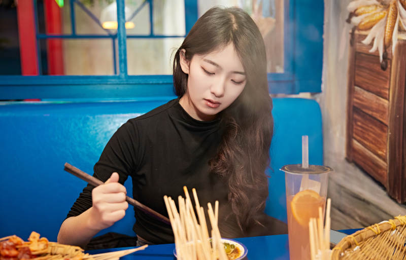 在饭馆吃成都串串的亚洲少女图片