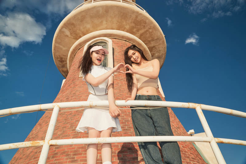 盛夏在景区湖边灯塔上拍照游玩的美女们图片