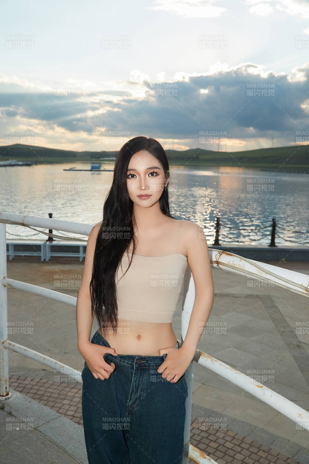 盛夏在景区湖边灯塔上拍照游玩的美女图片