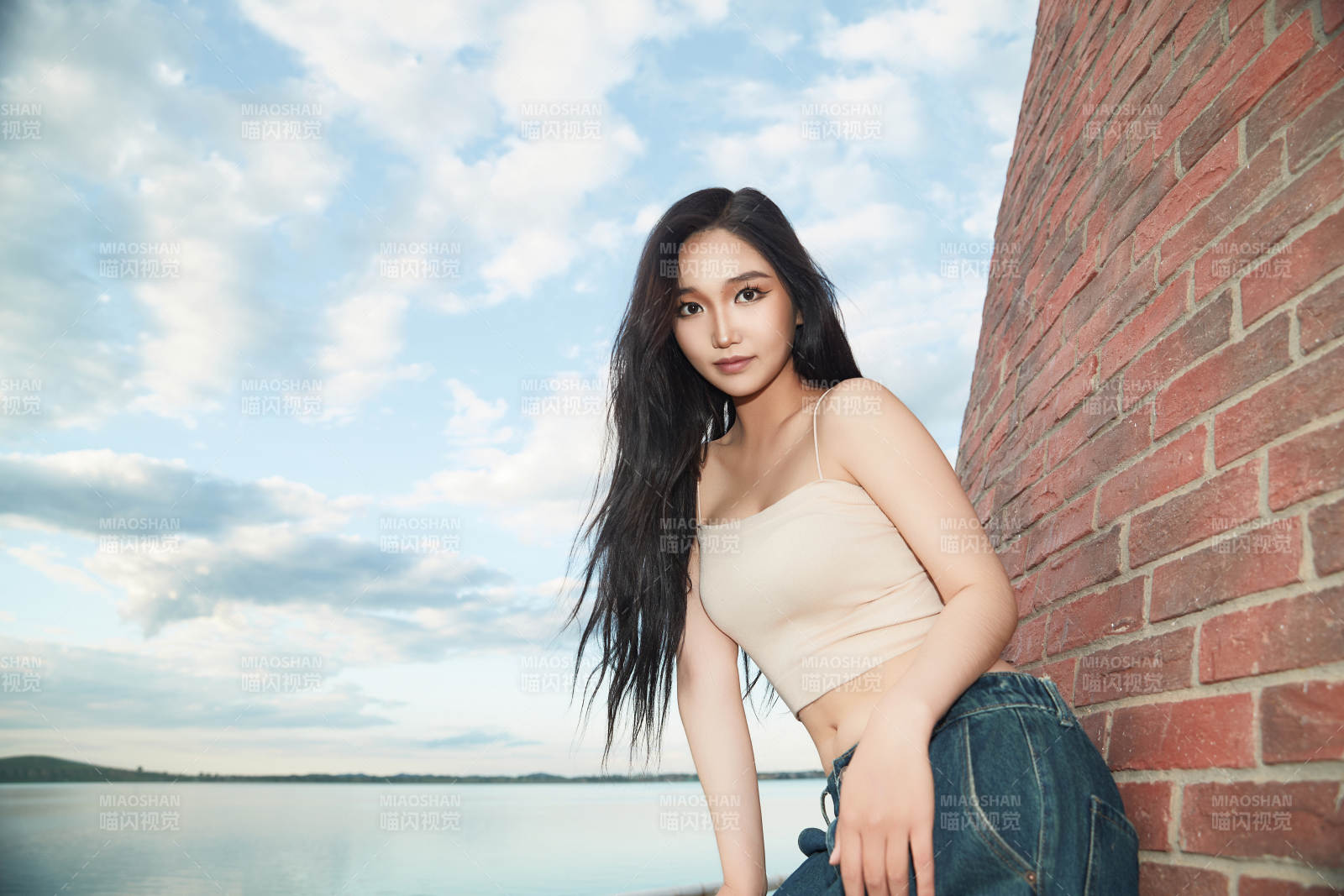 盛夏在景区湖边灯塔上拍照游玩的美女图片