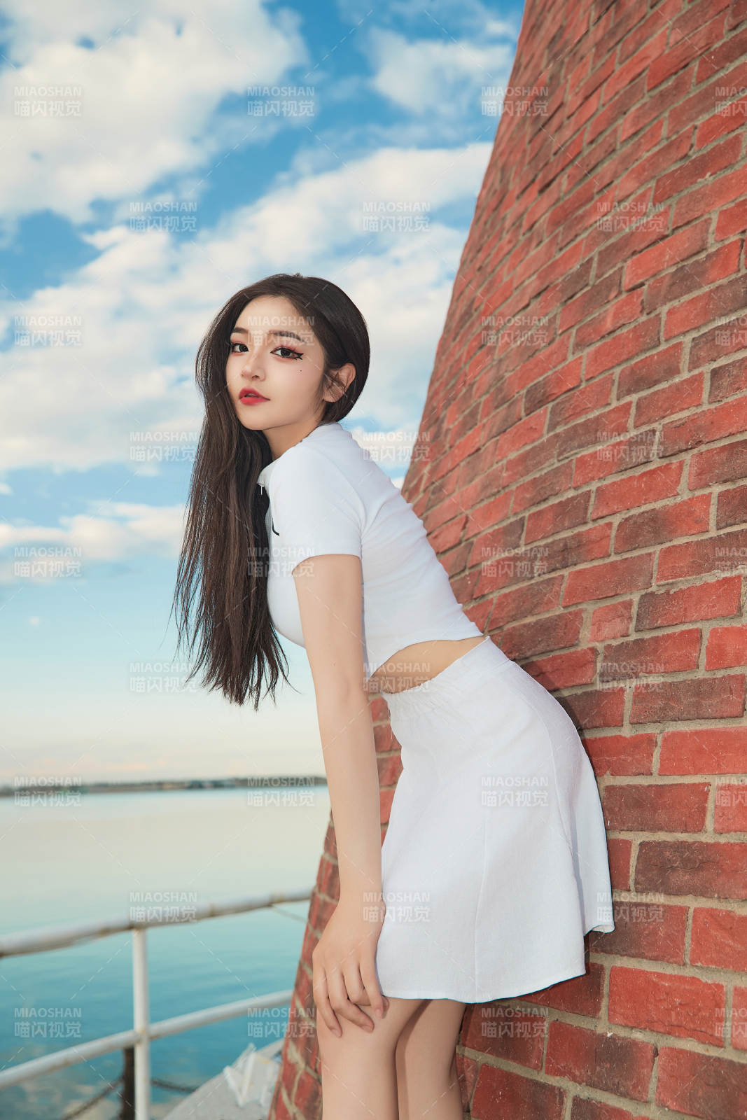 盛夏在景区湖边灯塔上拍照游玩的美女图片