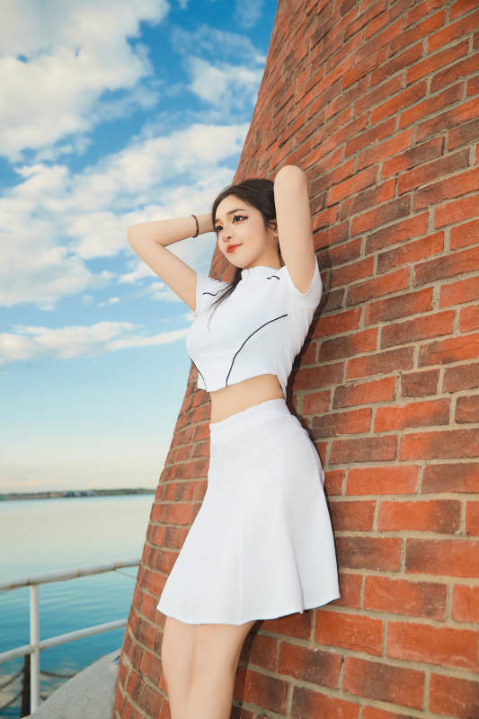 盛夏在景区湖边灯塔上拍照游玩的美女图片