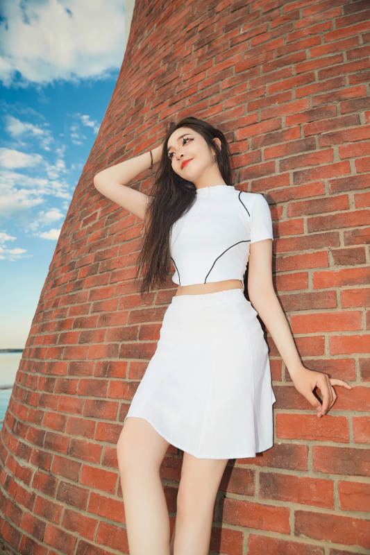 盛夏在景区湖边灯塔上拍照游玩的美女图片