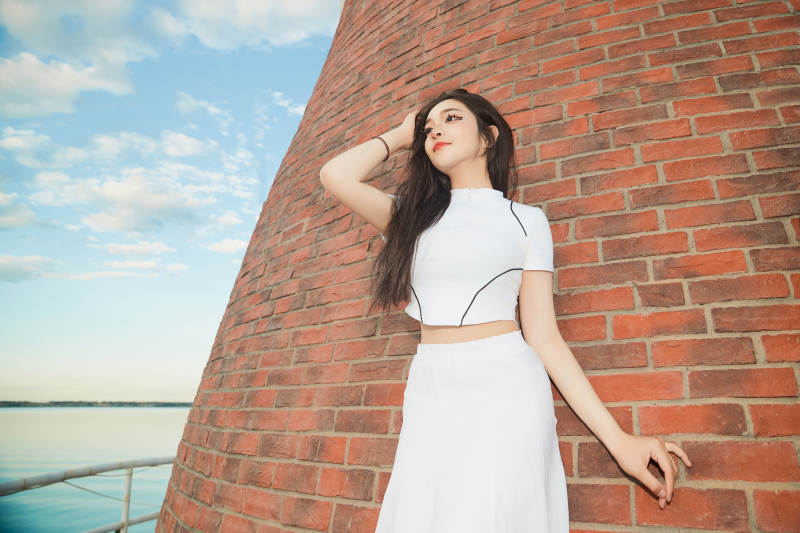 盛夏在景区湖边灯塔上拍照游玩的美女图片