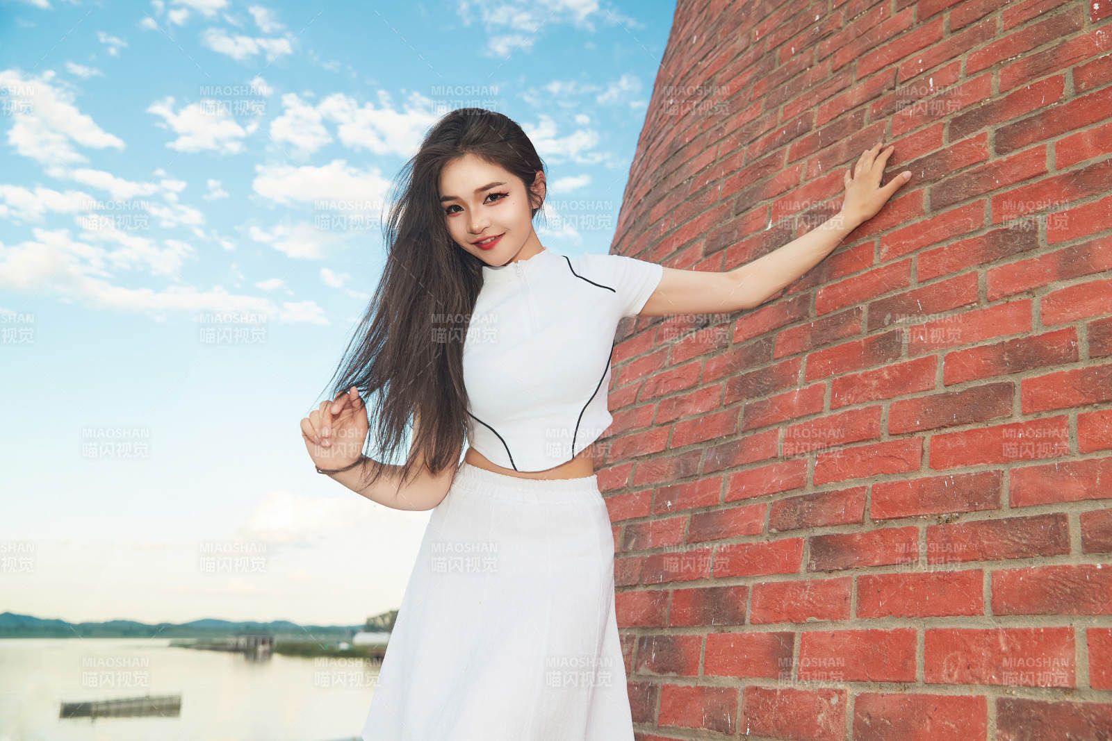 盛夏在景区湖边灯塔上拍照游玩的美女图片